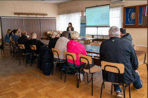 Zdjęcie przedstawia grupę ludzi siedzących i słuchających Doradcę Energetycznego