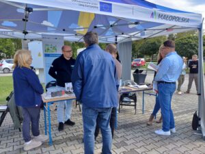 Na zdjeciu Doradca Energetyczny pod namiotem udzielajacy informacji 5 osobom